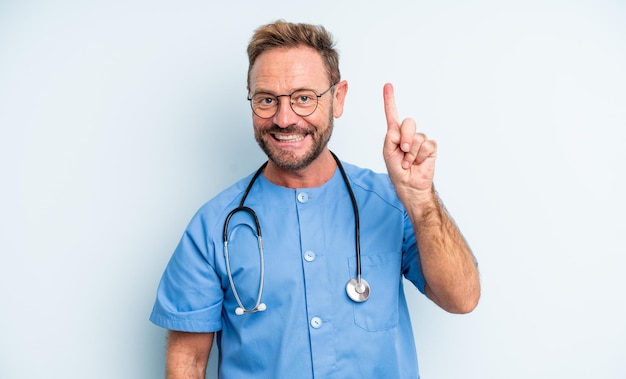 Middle age handsome man smiling and looking friendly, showing number one. nurse concept