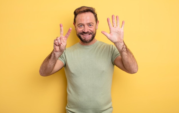 Middle age handsome man smiling and looking friendly, showing number seven or seventh with hand forward, counting down