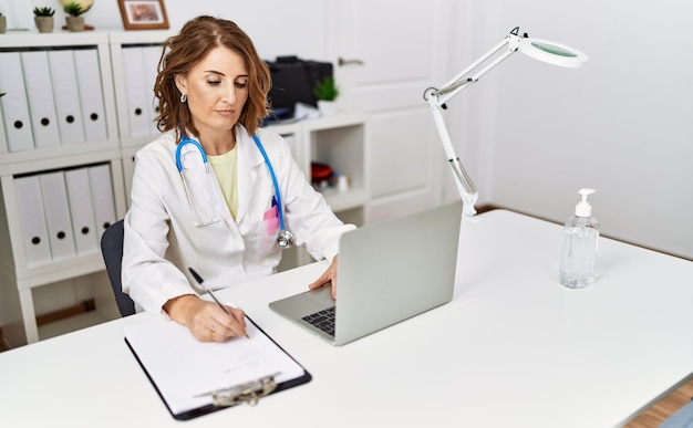 Middle age hispanic woman wearing doctor uniform working at clinic