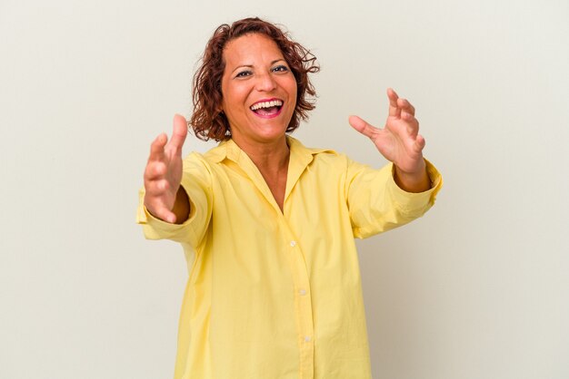 Middle age latin woman isolated on white background feels confident giving a hug to the camera.