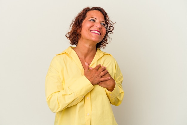 Middle age latin woman isolated on white background laughing keeping hands on heart, concept of happiness.