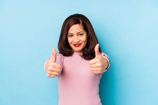 Middle age latin woman with thumbs ups, cheers about something