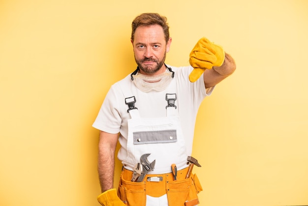 Photo middle age man feeling cross,showing thumbs down. handyman and repair concept