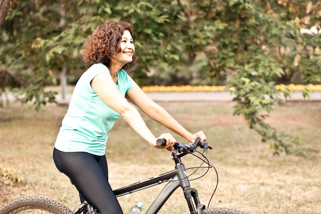 Middle age senior woman on bike cycle ride in countryside park outdoor.