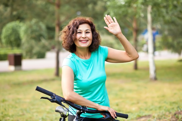 Middle age senior woman on bike cycle ride in countryside park outdoor.