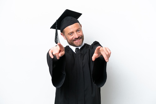 Middle age university graduate man isolated on white background points finger at you while smiling