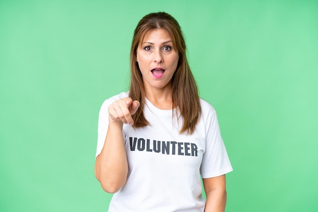 Middle age volunteer woman over isolated background surprised and pointing front