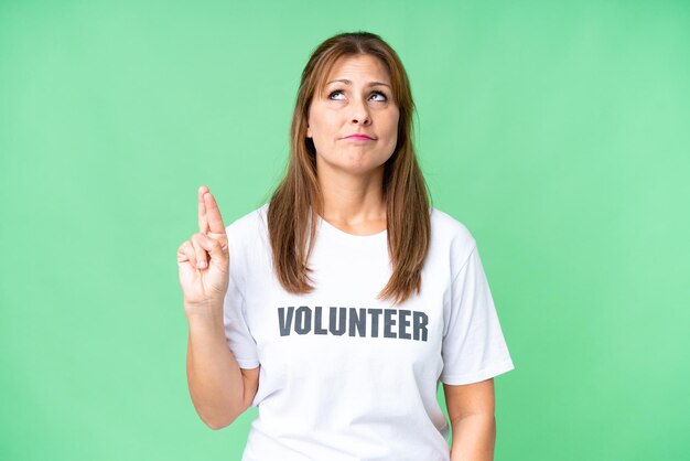 Middle age volunteer woman over isolated background with fingers crossing and wishing the best