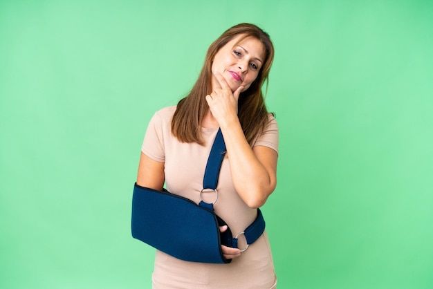 Middle age with broken arm and wearing a sling over isolated background happy and smiling