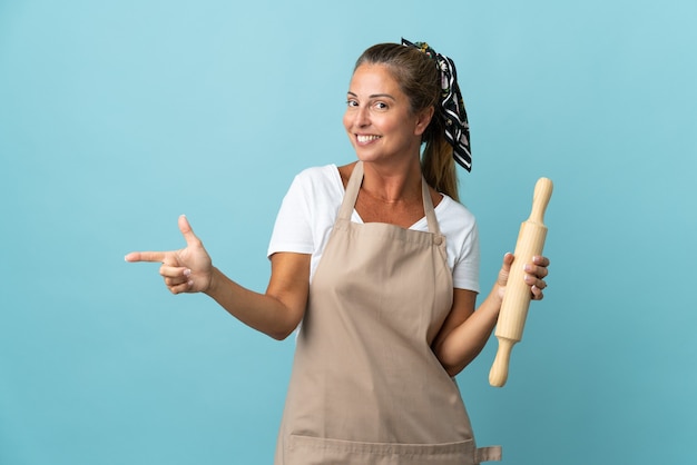 Middle age woman in chef uniform pointing finger to the side