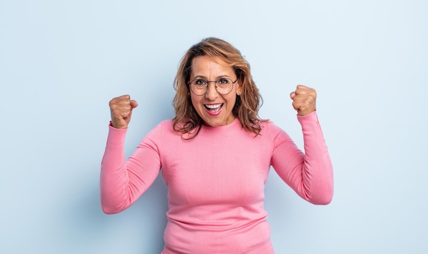 Middle age woman feeling happy positive and successful celebrating victory achievements or good luck