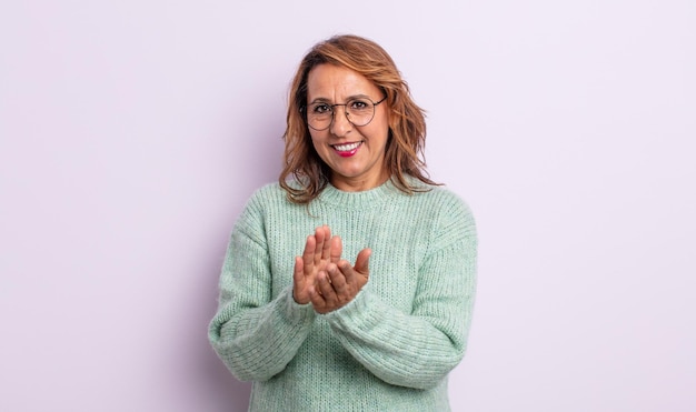 Photo middle age woman feeling happy and successful, smiling and clapping hands, saying congratulations with an applause