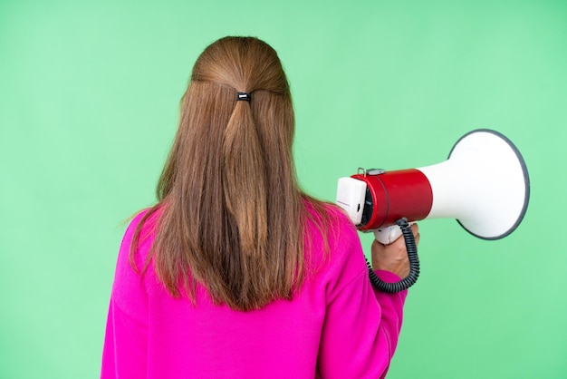 Middle age woman over isolated background holding a megaphone and in back position