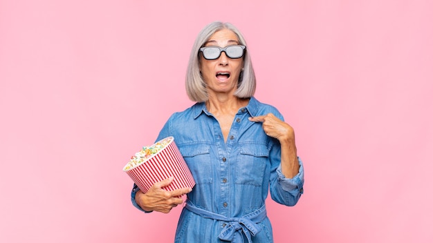 Middle age woman looking shocked and surprised with mouth wide open, pointing to self movie concept