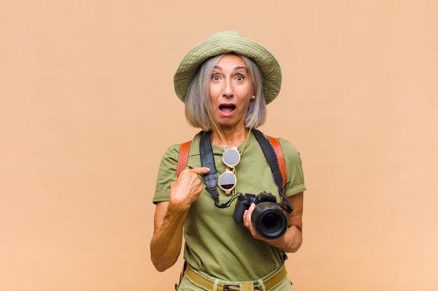 Middle age woman looking shocked and surprised with mouth wide open, pointing to self