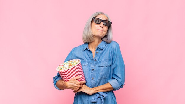 Middle age woman shrugging, feeling confused and uncertain, doubting with arms crossed and puzzled look movie concept