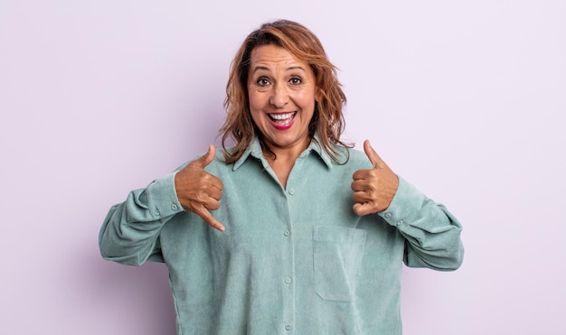 Photo middle age woman smiling broadly looking happy, positive, confident and successful, with both thumbs up