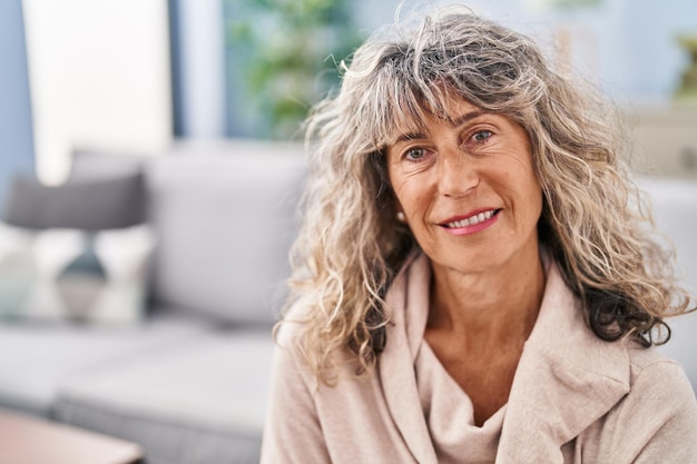 Middle age woman smiling confident sitting on sofa at home