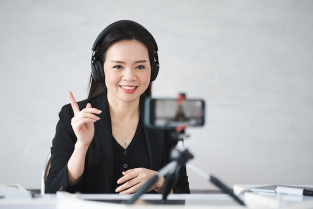 A middle-aged Asian woman teacher live online with smartphone at University