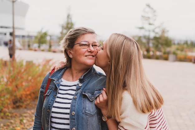 Middle aged blond mother and adult daughter walks and having fun in autumn park