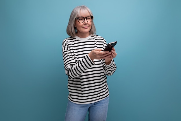 Middle aged business woman surfs the internet using smartphone on bright studio background