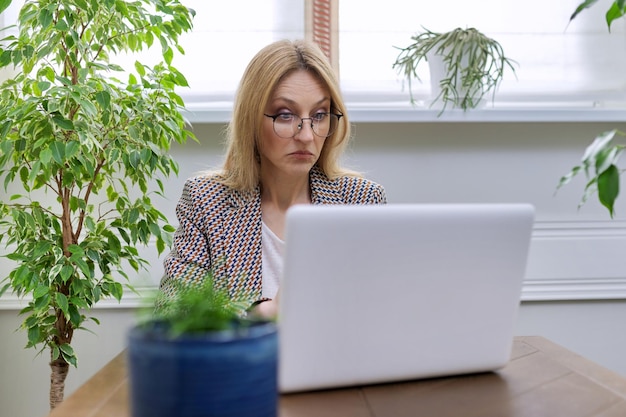 Middle aged business woman working at home using laptop