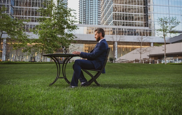 Middle aged businessman typing on laptop computer sitting at table on office terrace man working rem