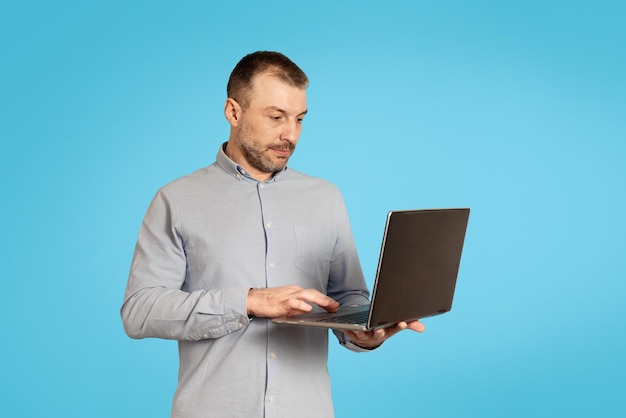 Middle Aged Businessman Using Laptop Computer Working Online Blue Background