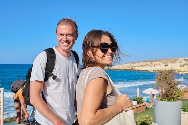 Middle-aged couple walking holding hands, man and woman traveling together