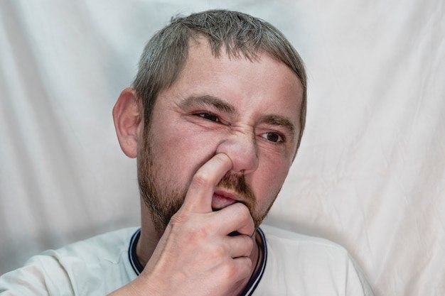 A middle-aged European man with a beard picks his nose with a finger.