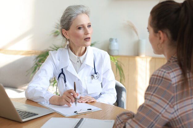 Middle aged female doctor therapist in consultation with patient in office.