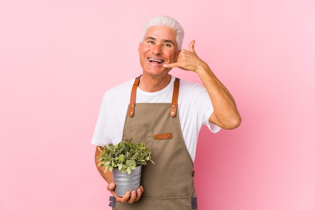 Middle aged gardener man isolated showing a mobile phone call gesture with fingers.