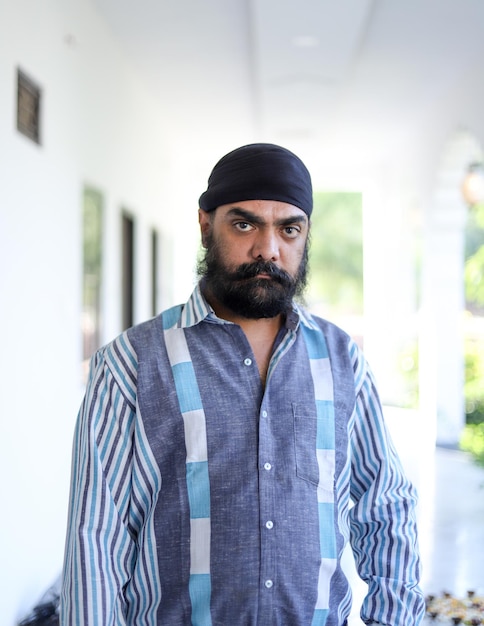 Middle-aged Indian man wearing a turban on his head and posing with a serious facial expression