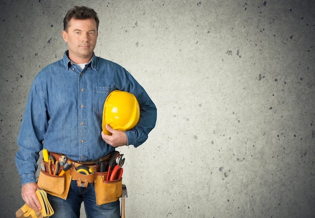 Middle aged male builder on gray wall background