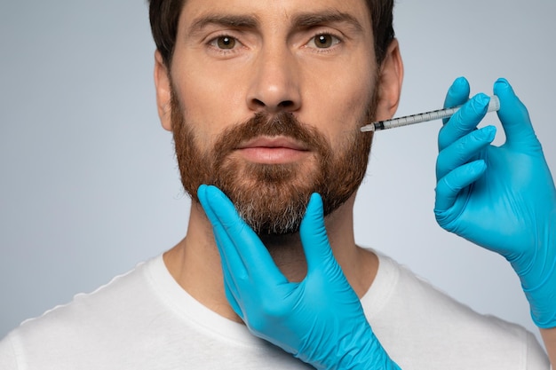 Middle aged man getting antiaging procedure at clinic or salon cosmetician hands in gloves making beauty injection