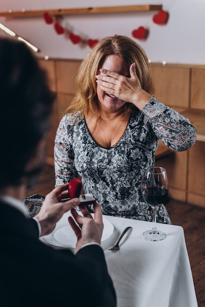 A middle aged man makes a marriage proposal to a woman at dinner.