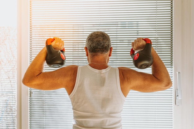 Middle-aged man, muscular build, demonstrates muscles of arms, is engaged in strength training