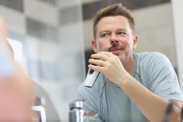 Middle aged man shaving beard with electronic machine