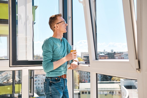 Middle aged man stands on balcony of highrise building