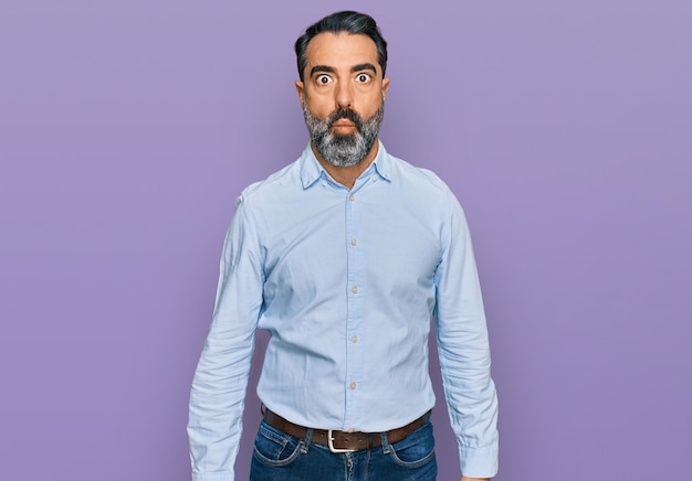 Middle aged man with beard wearing business shirt making fish face with lips, crazy and comical gesture. funny expression.