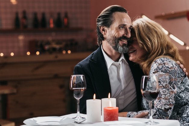 Middle-aged man and woman leaning against each other at a table in a restaurant