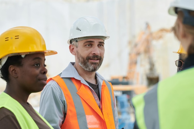 Middle aged manager of team of marble quarry workers talking to subordinates