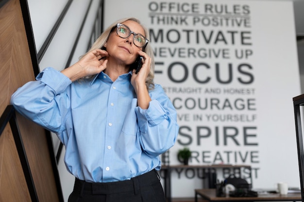 Middle aged older business woman executive in a classic blue shirt speaks on a mobile phone in the