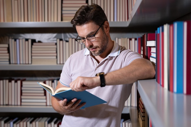 Middle aged teacher or professor in school library reading book teachers day teacher in classroom