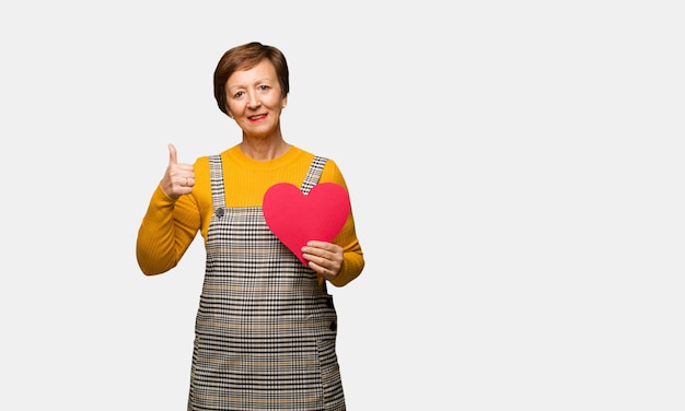 Middle aged woman celebrating valentines day smiling and raising thumb up