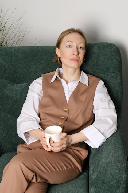 Middle aged woman having rest during coffee break in office recreation room