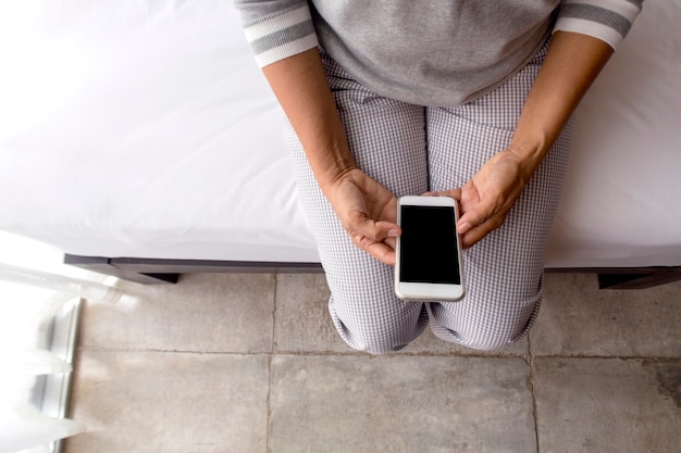 middle aged woman using smart phone in bed, top view.