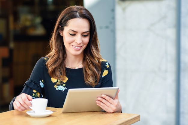 Middle-aged woman using tablet on coffee break in urban cafe bar