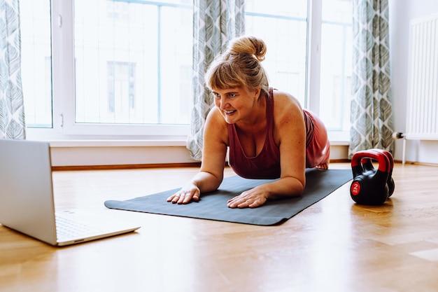 middle-aged woman with curvaceous figure, overweight, blonde, stands in plank position, does yoga,