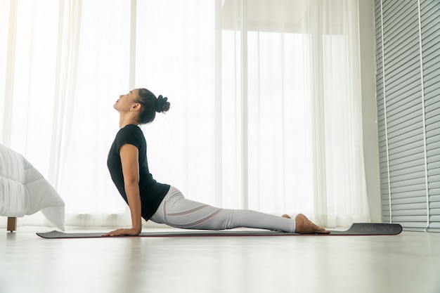 Middle aged women doing yoga in bedroom at the morning